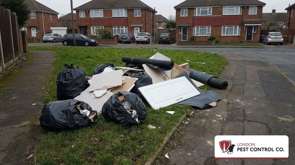 Fly-tipped waste heap of bin bags and builders rubble dumped on a suburban grass verge in Sutton, south London